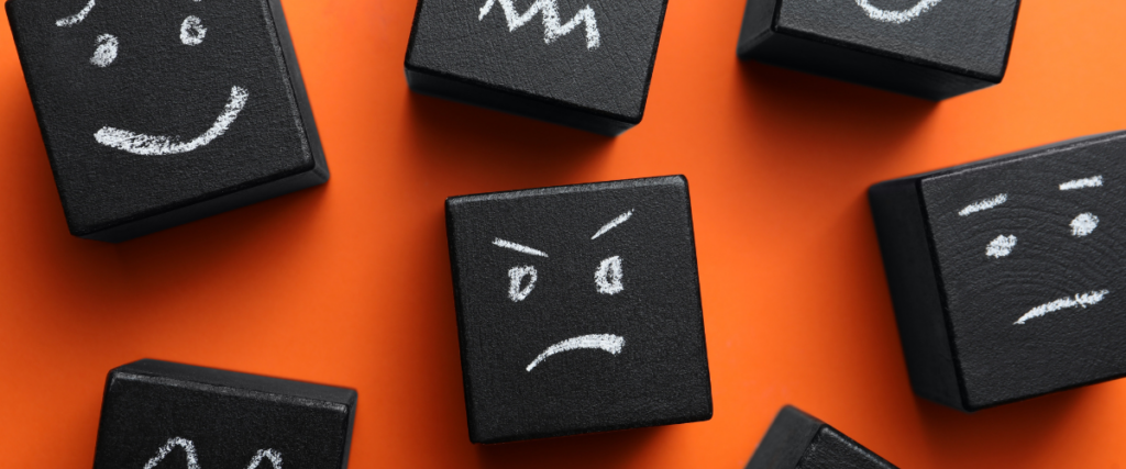 Chalk blocks on an orange background showing different emotions which can help in understanding others